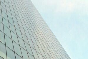 Glass building with transparent facade of the building and blue sky. Structural glass wall reflecting blue sky. Abstract modern architecture fragment. Contemporary architectural background. photo