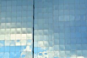 Glass building with transparent facade of the building and blue sky. Structural glass wall reflecting blue sky. Abstract modern architecture fragment. Contemporary architectural background. photo