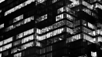 Pattern of office buildings windows illuminated at night. Glass architecture ,corporate building at night - business concept. Black and white. photo