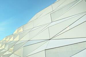 Abstract closeup of the glass-clad facade of a modern building covered in reflective plate glass. Architecture abstract background. Glass wall and facade detail. photo