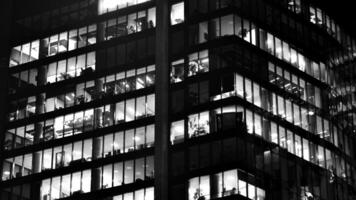 Pattern of office buildings windows illuminated at night. Glass architecture ,corporate building at night - business concept. Black and white. photo