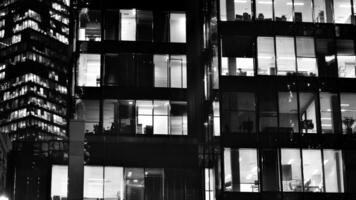 Pattern of office buildings windows illuminated at night. Glass architecture ,corporate building at night - business concept. Black and white. photo