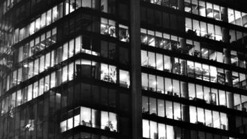 Pattern of office buildings windows illuminated at night. Glass architecture ,corporate building at night - business concept. Black and white. photo