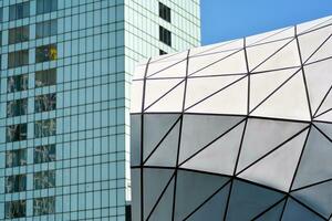 Abstract closeup of the glass-clad facade of a modern building covered in reflective plate glass. Architecture abstract background. Glass wall and facade detail. photo