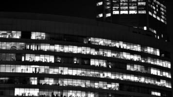 Pattern of office buildings windows illuminated at night. Glass architecture ,corporate building at night - business concept. Black and white. photo