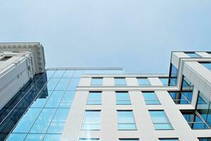 Abstract closeup of the glass-clad facade of a modern building covered in reflective plate glass. Architecture abstract background. Glass wall and facade detail. photo