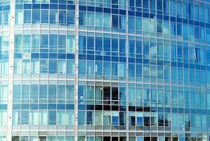 Glass building with transparent facade of the building and blue sky. Structural glass wall reflecting blue sky. Abstract modern architecture fragment. Contemporary architectural background. photo