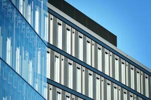 Abstract closeup of the glass-clad facade of a modern building covered in reflective plate glass. Architecture abstract background. Glass wall and facade detail. photo