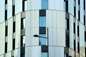 Abstract closeup of the glass-clad facade of a modern building covered in reflective plate glass. Architecture abstract background. Glass wall and facade detail. photo