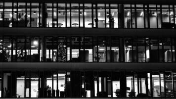 Pattern of office buildings windows illuminated at night. Glass architecture ,corporate building at night - business concept. Black and white. photo