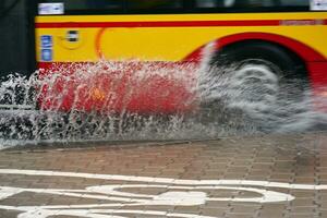 Splashes from under the wheels of the bus during heavy rain. Blurred bus. photo