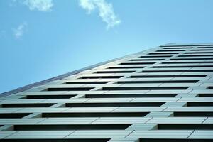 Abstract closeup of the glass-clad facade of a modern building covered in reflective plate glass. Architecture abstract background. Glass wall and facade detail. photo