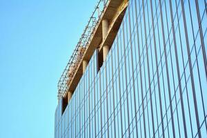 High rise building under construction. Installation of glass facade panels on a reinforced concrete structure. photo