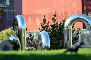 Public art installation in front modern building.Decorative stainless steel pipes photo