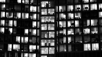 Pattern of office buildings windows illuminated at night. Glass architecture ,corporate building at night - business concept. Black and white. photo