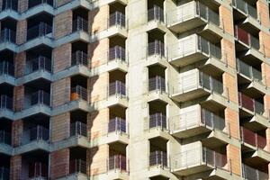 High rise building under construction. Installation of glass facade panels on a reinforced concrete structure. photo