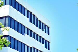 Abstract closeup of the glass-clad facade of a modern building covered in reflective plate glass. Architecture abstract background. Glass wall and facade detail. photo