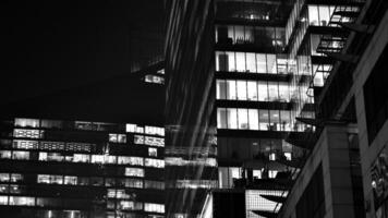 Pattern of office buildings windows illuminated at night. Glass architecture ,corporate building at night - business concept. Black and white. photo