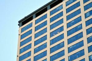 Glass building with transparent facade of the building and blue sky. Structural glass wall reflecting blue sky. Abstract modern architecture fragment. Contemporary architectural background. photo