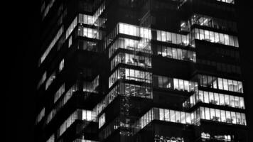 Pattern of office buildings windows illuminated at night. Glass architecture ,corporate building at night - business concept. Black and white. photo