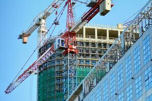 High rise building under construction. Installation of glass facade panels on a reinforced concrete structure. photo