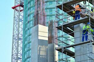 High rise building under construction. Installation of glass facade panels on a reinforced concrete structure. photo