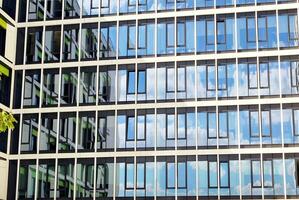 Abstract closeup of the glass-clad facade of a modern building covered in reflective plate glass. Architecture abstract background. Glass wall and facade detail. photo