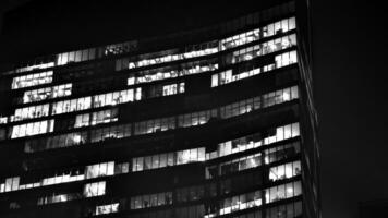 Pattern of office buildings windows illuminated at night. Glass architecture ,corporate building at night - business concept. Black and white. photo