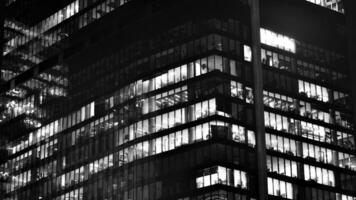 Pattern of office buildings windows illuminated at night. Glass architecture ,corporate building at night - business concept. Black and white. photo