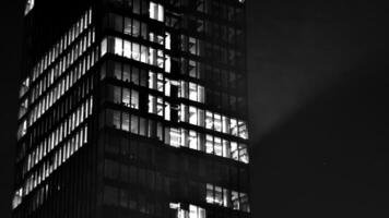 Pattern of office buildings windows illuminated at night. Glass architecture ,corporate building at night - business concept. Black and white. photo