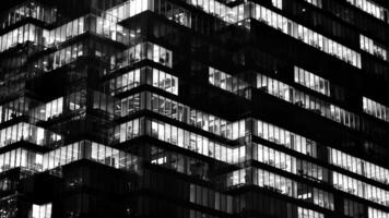 Pattern of office buildings windows illuminated at night. Glass architecture ,corporate building at night - business concept. Black and white. photo