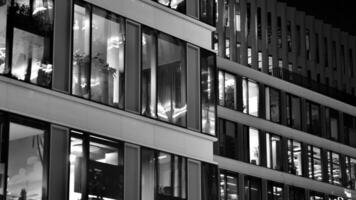 Pattern of office buildings windows illuminated at night. Glass architecture ,corporate building at night - business concept. Black and white. photo