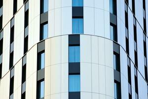 Abstract closeup of the glass-clad facade of a modern building covered in reflective plate glass. Architecture abstract background. Glass wall and facade detail. photo