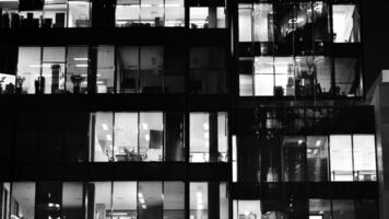 Pattern of office buildings windows illuminated at night. Glass architecture ,corporate building at night - business concept. Black and white. photo