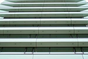 Abstract closeup of the glass-clad facade of a modern building covered in reflective plate glass. Architecture abstract background. Glass wall and facade detail. photo