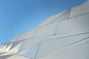 Abstract closeup of the glass-clad facade of a modern building covered in reflective plate glass. Architecture abstract background. Glass wall and facade detail. photo