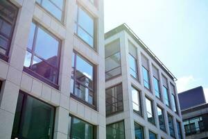 Abstract closeup of the glass-clad facade of a modern building covered in reflective plate glass. Architecture abstract background. Glass wall and facade detail. photo