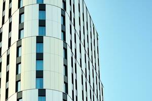 Abstract closeup of the glass-clad facade of a modern building covered in reflective plate glass. Architecture abstract background. Glass wall and facade detail. photo