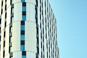 Abstract closeup of the glass-clad facade of a modern building covered in reflective plate glass. Architecture abstract background. Glass wall and facade detail. photo