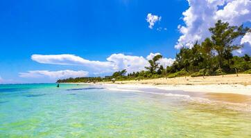 Tropical Caribbean beach people parasols fun Playa del Carmen Mexico. photo