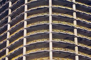 High rise building under construction. Installation of glass facade panels on a reinforced concrete structure. photo