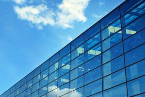 vaso edificio con transparente fachada de el edificio y azul cielo. estructural vaso pared reflejando azul cielo. foto