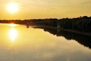 River in the city in at colorful sunset in the background photo