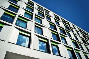 Abstract closeup of the glass-clad facade of a modern building covered in reflective plate glass. Architecture abstract background. Glass wall and facade detail. photo