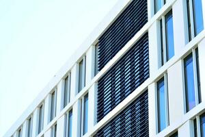 Abstract closeup of the glass-clad facade of a modern building covered in reflective plate glass. Architecture abstract background. Glass wall and facade detail. photo