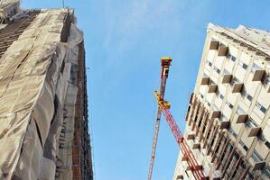 High rise building under construction. Installation of glass facade panels on a reinforced concrete structure. photo