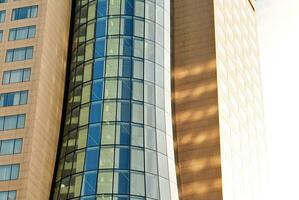 Abstract closeup of the glass-clad facade of a modern building covered in reflective plate glass. Architecture abstract background. Glass wall and facade detail. photo