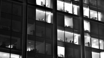 Pattern of office buildings windows illuminated at night. Glass architecture ,corporate building at night - business concept. Black and white. photo