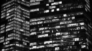 Pattern of office buildings windows illuminated at night. Glass architecture ,corporate building at night - business concept. Black and white. photo