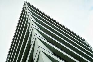 Abstract closeup of the glass-clad facade of a modern building covered in reflective plate glass. Architecture abstract background. Glass wall and facade detail. photo